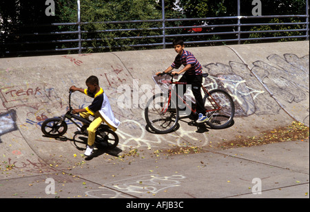 Les jeunes enfants sur les vélos BMX sur rampes de skate park. Banque D'Images