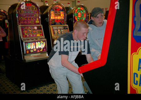 Jeune homme jouant aux machines à sous dans un jeux d'arcade. Banque D'Images