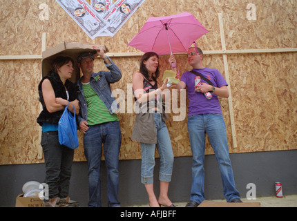 Les jeunes s'abritant sous des parapluies pendant une tempête de pluie dans les rues de Londres. Banque D'Images