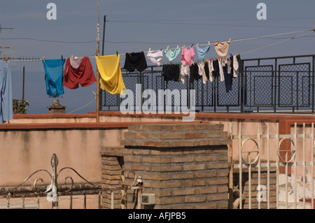 Blanchisserie colorés accrochés sur une corde à linge sur certains murs de briques et de stuc et de clôtures en fer forgé avec ciel bleu et la mer derrière Banque D'Images