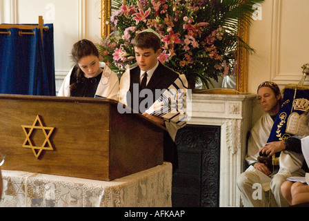 Garçon et fille Batmitzvah Barmitzvah (jumeaux) diriger la cérémonie à leur Bar/Bat Mitzvah avec man holding de Torah dans backgrou Banque D'Images