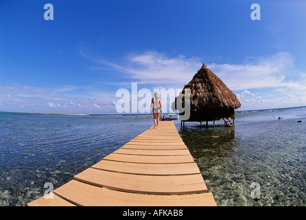 Femme dans le passage libre vers au-dessus de l'eau bungalow palapa au Belize Caraïbes et modèle droit parution propriété Banque D'Images