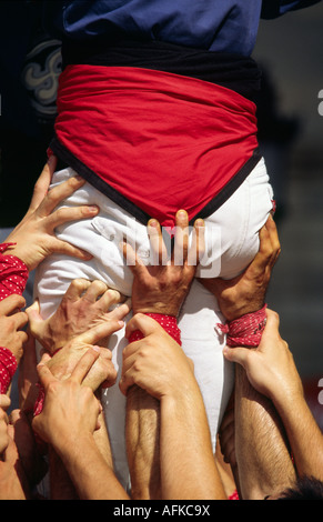 De nombreuses mains aident à soutenir la base d'un château pendant le festival de la Merce à Barcelone. Banque D'Images
