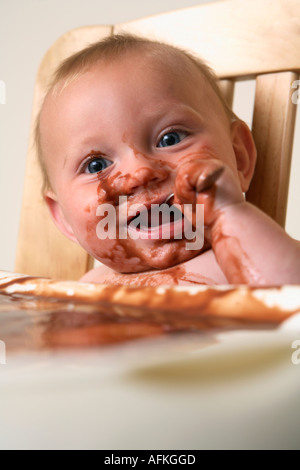 Chaise haute bébé en faisant le pouding au chocolat avec mess Banque D'Images