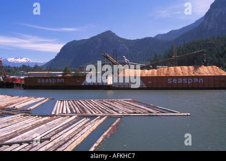 Les copeaux de bois chargé sur une barge pour le transport vers les marchés et d'estacades en premier plan de la Colombie-Britannique Canada Banque D'Images