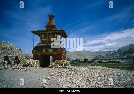 Le Népal l'Asie du Sud de l'himalaya Mustang peint ancien marquage stupa entrée de Tsarang avec deux cavaliers approche dans la vallée Banque D'Images