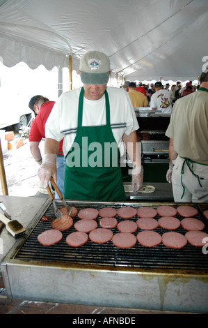 La cuisson des hamburgers sur un gril pendant à la vente lors d'un festival Banque D'Images