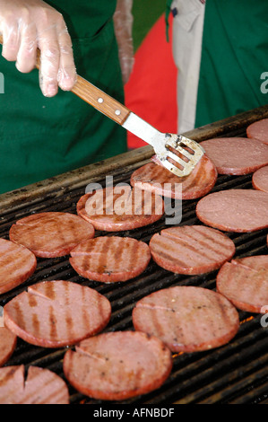 La cuisson des hamburgers sur un gril pendant à la vente lors d'un festival Banque D'Images