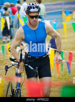 Homme qui court avec son vélo dans la compétition de triathlon Banque D'Images
