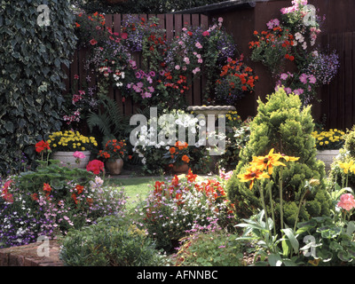 National de résidence typiquement anglais jardin arrière partie de pelouse avec des plantes à massifs dans des paniers d'une baignoire Bain d'oiseaux Banque D'Images