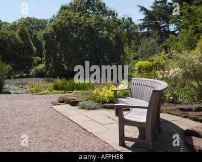 NESS Botanic Gardens banquette en bois courbé et étang dans rock garden Cheshire England UK Neston Banque D'Images