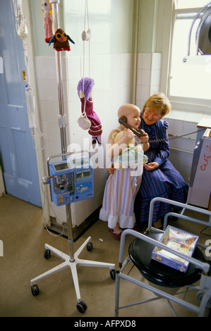 NHS pupille 1980s. Enfant atteint d'un cancer dont la mère s'occupe fait un appel téléphonique dans le couloir. Alder Hey Hospital Liverpool 1988 Royaume-Uni Banque D'Images