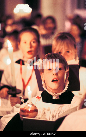 Enfants les enfants chantent dans la chorale de l'école Christingle église de Noël. service. Tenant des bougies allumées avec orange Leighton Buzzard des années 1990 UK England Banque D'Images