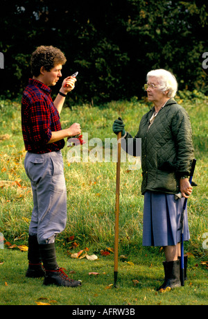 Vieille Femme EN CONVERSATION AVEC JEUNE HOMME DANS LES JARDIN JARDINAGE GLOUCESTERSHIRE UK HOMER SYKES Banque D'Images