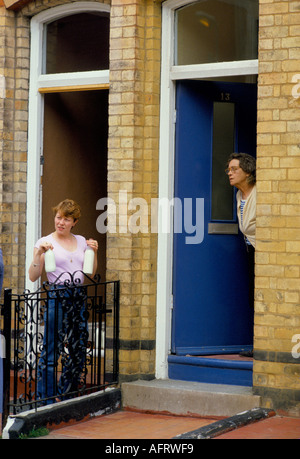 Voisins juste à côté sur la porte d'entrée de leurs maisons mitoyennes jointives. Deux pintes de lait dans des bouteilles de lait. Londres Angleterre Royaume-Uni des années 1980 HOMER SYKES Banque D'Images