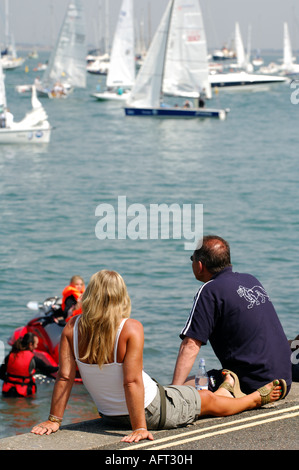 Les jeunes met la femme couple regardant le yacht racing au cours de la semaine de Cowes en été sur l'île de Wight Banque D'Images