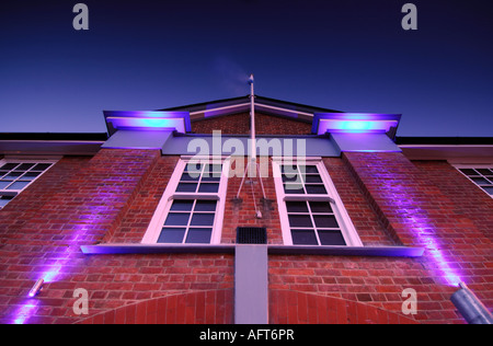 L'éclairage par projection sur un vieux bâtiment édouardien victorien à la recherche jusqu'au ciel avec deux conemporary lumières stobe en violet mauve Banque D'Images