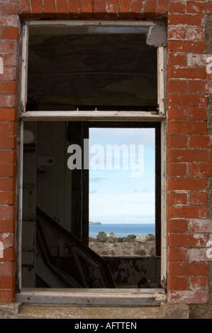 Grâce à la fenêtre cassée du vieux bâtiment abandonné par l'autre côté vers le nord Côte d'Antrim au-delà chambre avec vue Banque D'Images