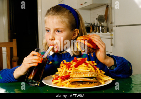 Jeune écolière de manger un énorme hamburger-frites coke potable à Londres après l'école. HOMER SYKES Banque D'Images