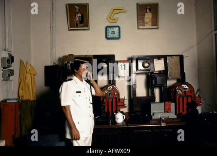 Chef de station PARLANT AU TÉLÉPHONE EN FONCTION LORS DE LA GARE de Bukit Timah. Singapour HOMER SYKES Banque D'Images