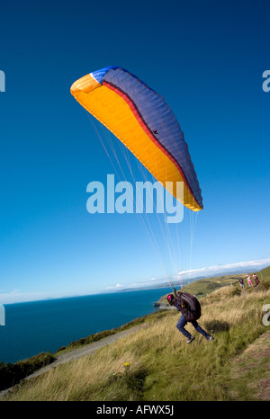 Homme avec para planeur de décoller sur Constitution hill Aberystwyth donnant sur la baie de Cardigan sur un ciel bleu ciel été jour UK Banque D'Images