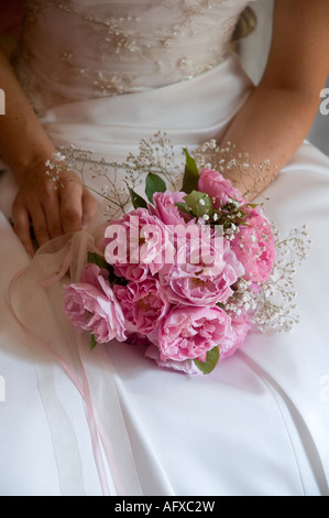 Bouquet bouquet de mariée style tenue en main sur robe de satin blanc Banque D'Images