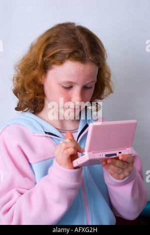 Une jeune fille de 11 ans de jouer sur une machine de jeu Nintendo DS Lite à l'aide d'un stylet Banque D'Images