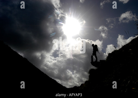 Un randonneur qui se découpent sur l'éperon rocheux contre le ciel sur le South West Coast Path, Devon, UK Banque D'Images