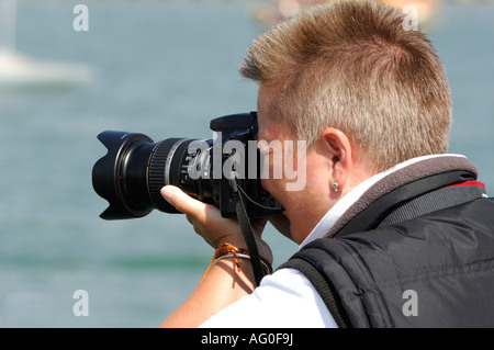 Un homme à l'aide d'un appareil photo reflex numérique reflex numérique avec son œil au viseur de prendre une photo Banque D'Images