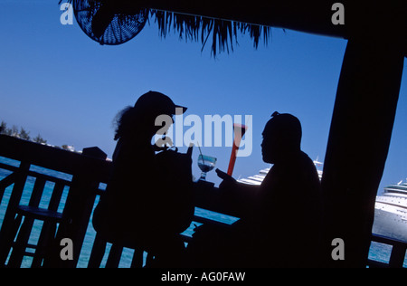 Jeune couple ayant des boissons dans un bar qui donne sur le port de Nassau Bahamas Banque D'Images