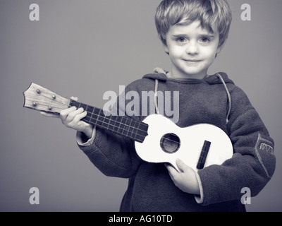 Garçon faisant semblant d'être une rock star avec petits enfants ukulélé ukulélé boy play air Banque D'Images