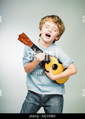 Garçon faisant semblant d'être une rock star avec petits enfants ukulélé ukulélé Banque D'Images