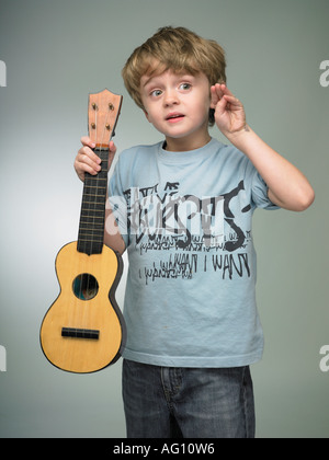 Garçon faisant semblant d'être une rock star avec petit instrument ukulélé ukulélé childs chaîne classique Banque D'Images