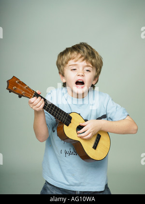 Garçon faisant semblant d'être une rock star avec petite guitare de childs Banque D'Images