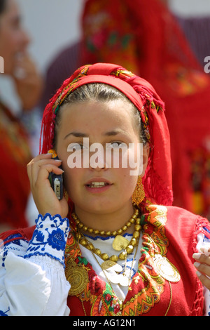 Fille sur téléphone mobile - lors de fêtes au Portugal, une jeune fille habillée d'une robe traditionnelle utilise son téléphone portable Banque D'Images