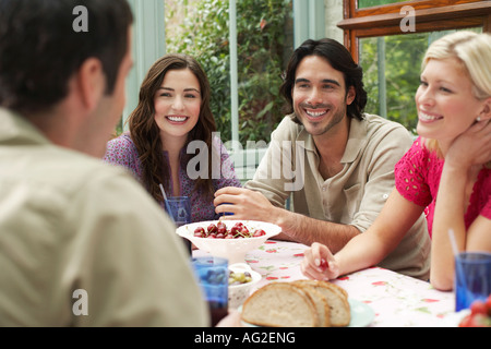 Groupe de jeunes gens assis au Verandah table, laughing Banque D'Images
