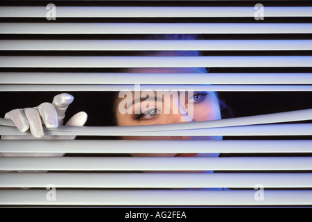 Femme regardant par jalousie Banque D'Images