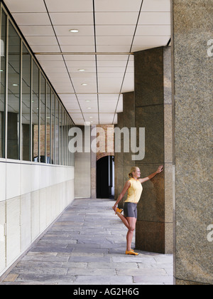 Woman stretching contre un pilier Banque D'Images