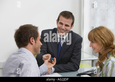 Couple in estate agents, agent immobilier handing man pens Banque D'Images