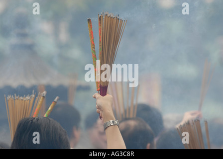 Soleil brûlant holding joss sticks pendant les célébrations du Nouvel An lunaire dans le temple de Wong Tai Sin, Kowloon. Hong Kong, Chine Banque D'Images