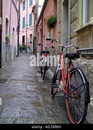 Les vélos garés dans la ruelle avec les bâtiments et les dalles humides rose après la pluie au Cinque Terre Italie Banque D'Images