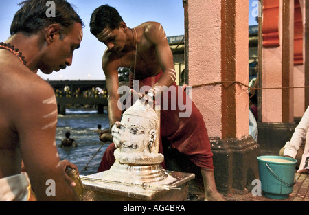 Le Seigneur Shiva lingam Idole de dieu indien lavées avec du beurre lait caillé par deux prêtres au Maharashtra Nasik Godavari Inde Asie Banque D'Images