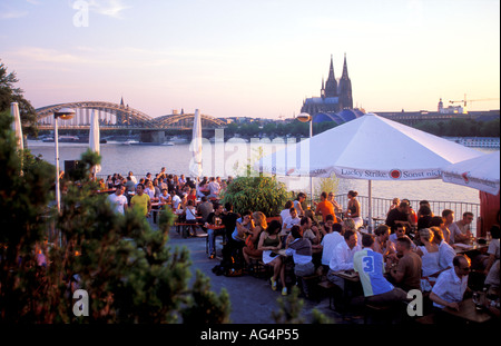 Les gens assis au bar et restaurant Rheinterrassen branché avec une vue sur la vieille ville et la Cathédrale, Cologne, Allemagne Banque D'Images