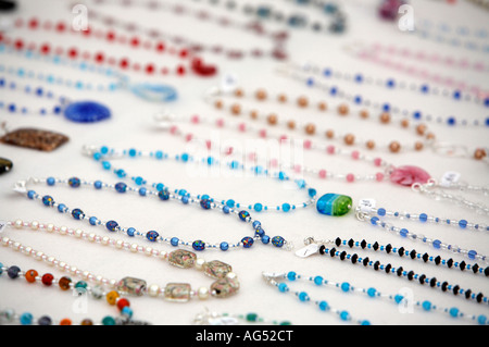 Ligne de bijoux colliers bon marché accueil fait sur une nappe blanche sur un étal Banque D'Images