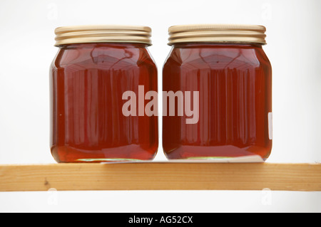 Deux pots de miel foncé assis sur une planche en bois Banque D'Images