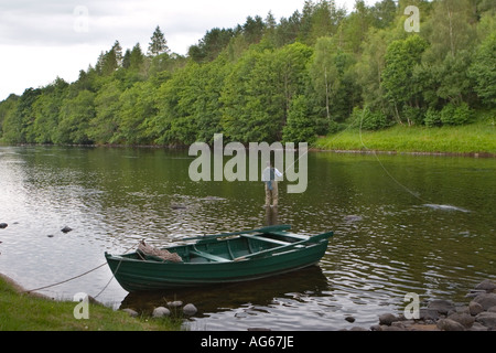 Volent pêcheur dans les waders avec des ghilies bateau amarré, transportant le filet d'atterrissage, barboter dans la rivière Spey, Speyside, Castle Grant beat, Écosse Royaume-Uni Banque D'Images