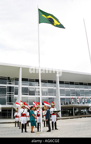 Couple de hautes autorités soulevant le drapeau national devant le palais présidentiel dans la capitale fédérale - Brasilia - BR Banque D'Images