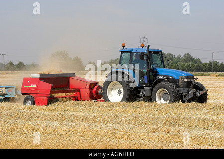 Tracteur New Holland et une ramasseuse-presse Welger Lely AP830 de la mise en balles de paille dans un champ dans le Hertfordshire, Angleterre Banque D'Images