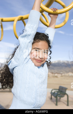 Dix ans fille se balançant sur monkey bars, d'école, l'ethnicité hispanique Banque D'Images