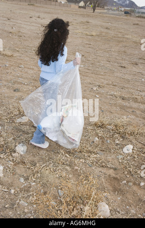 Dix ans, fille hispanique picking up trash, champ ouvert, sud-ouest des États-Unis Banque D'Images